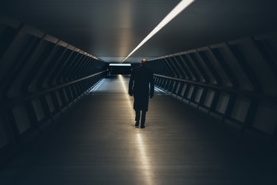 人穿黑色长袖衬衫走在隧道
